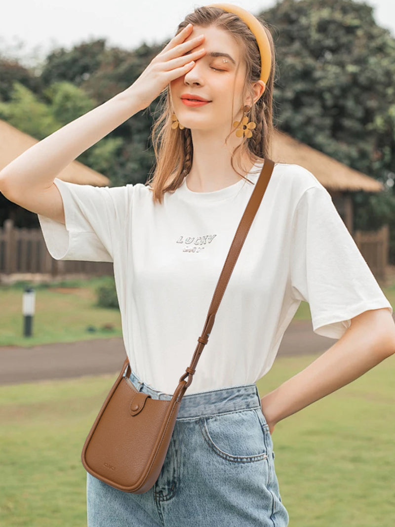Small crossbody phone bag with adjustable strap in tan waxed canvas worn over shoulder